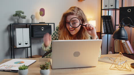 Businesswoman-working-at-office-holding-magnifying-glass-looking-at-laptop-screen-wow-expression