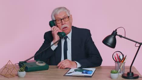 Crazy-senior-businessman-talking-on-wired-vintage-telephone,-fooling,-making-silly-humor-comic-faces