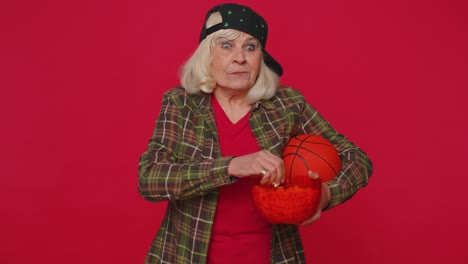 Elderly-senior-old-woman-basketball-fan-eating-popcorn-doing-winner-gesture,-celebrating-victory-win