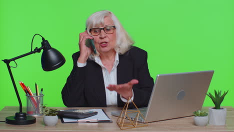 Enojada-Anciana-Mujer-De-Negocios-Haciendo-Una-Llamada-Telefónica-En-El-Trabajo-De-Oficina-Jefe-Molesto-Hablando-Pelea-Móvil