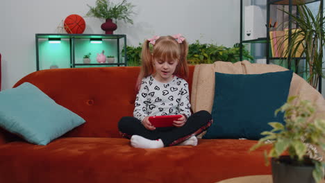 Worried-teen-child-girl-kid-enthusiastically-playing-shooter-video-online-game-on-smartphone-at-home