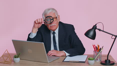 Investigator-senior-businessman-holding-magnifying-glass-near-face-looking-with-big-zoomed-funny-eye