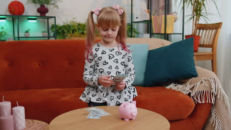 Little-toddler-kid-girl-counting-money-dollar-banknotes-for-future-needs-at-home-desk-with-piggybank