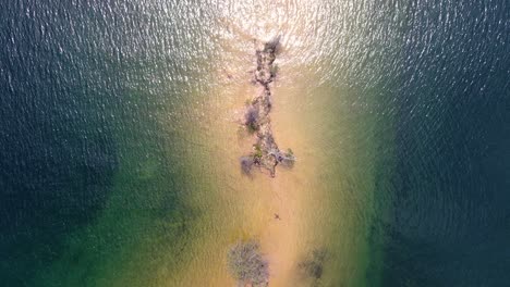 Aerial-top-view-drone-shot-capturing-the-shoreline-of-a-serene-lake-as-the-drone-glides-forward-into-the-expansive-blue-of-the-water-in-Whiskeytown-Reservoir,-California