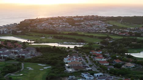Drone-trucking-pan-above-resort-with-golf-course-by-the-Caribbean-ocean-at-sunset
