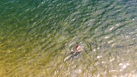 Drone-video-of-a-person-swimming-in-a-crystal-clear-lake-in-Whiskeytown-Reservoir,-California