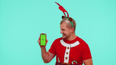 Mann-Im-T-Shirt-Mit-Weihnachtsmann-Und-Hirschgeweih-Zeigt-Mobiltelefon-Mit-Greenscreen-Chroma-Key