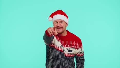 Man-in-red-Christmas-sweater-smiling-excitedly,-pointing-to-camera,-beauty-choosing-lucky-winner