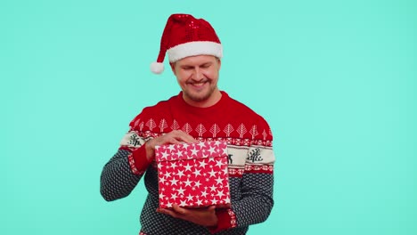 Man-in-Christmas-red-sweater-hat-smiling,-unwrapping-gift,-opening-box-with-pet-cat,-great-surprise