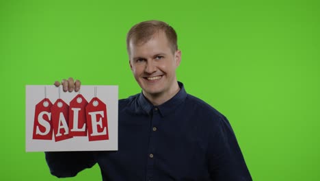 Happy-man-holding-Sale-word-inscription-and-showing-Ok-sign.-Guy-rejoicing-with-good-sale-discounts