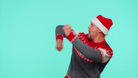 Young-adult-man-in-sweater-Santa-Christmas-hat-jumps-from-below-dancing-fooling-around-having-fun