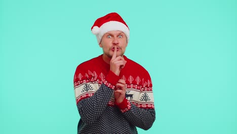 Der-Mann-Trägt-Einen-Roten-Weihnachtspullover,-Drückt-Den-Zeigefinger-An-Die-Lippen-Und-Macht-Ein-Zeichen-Der-Stille,-Ein-Geheimnis
