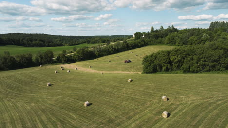 Establishing-aerial-of-agriculture-field-harvested-with-Hay-bale-with-tractor