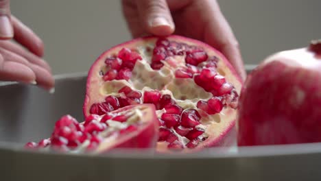 Close-up-of-Opening-up-a-big-red-Pomegranate-sitting-on-white-plate-on-table-healthy-anti-oxidants-cardioprotective-properties