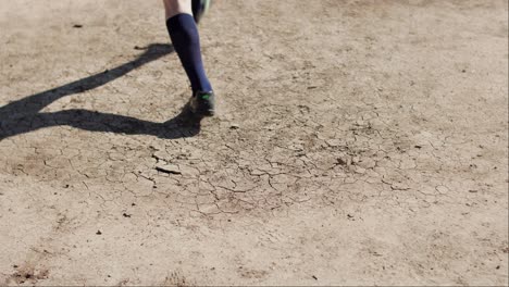 Close-shot-of-a-football-soccer-player-kicking-the-leather-ball-on-dry-dirt-floor