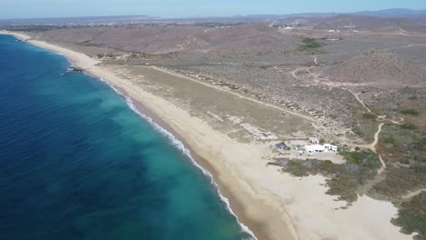 Wide-drone-shot-of-Los-Cerritos-beach-on-a-sunny-day-with-the-blue-water-waves-crashing-in-Mexico,-Todos-Santos