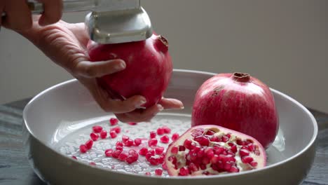 Pounding-a-half-of-a-big-red-pomegranate-juices-flowing-out-Pomegranate-sitting-on-white-plate-healthy-anti-oxidants-cardioprotective-properties