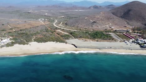 Aerial-view-of-Playa-Hotel-San-Cristobal-Todos-Santos-Baja-California-Sur,-panning-drone-footage-of-clear-blue-ocean-waters-and-white-sandy-beaches