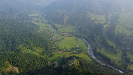 River-Meandering-Through-Lush-Green-Rural-Landscape-With-Fog-In-Nepal