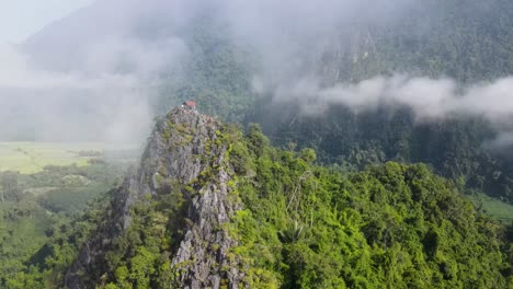 Luftaufnahmen,-Die-An-Schwebenden-Wolken-Mit-Den-Bewaldeten-Bergen-Von-Vang-Vieng-Vorbeifliegen-Und-Den-Aussichtspunkt-Nam-Xay-Freigeben
