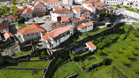 Drone-ascends-above-castle-walls-of-white-walled-facade-with-orange-roof-in-Vinhais,-Braganza,-Portugal