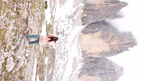 Woman-hiker-in-pink-raincoat-spins-happily-at-Tre-Cime-di-Lavaredo-base,-Italy