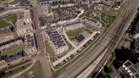 Noorderhaven-neighbourhood-in-Zutphen,-The-Netherlands,-seen-from-above-with-rooftops-full-of-solar-panels-along-train-tracks
