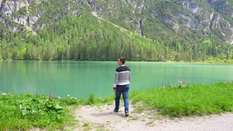 Man-walks-along-dirt-path-admiring-natural-beauty-of-Lago-di-Landro-in-Dolomites