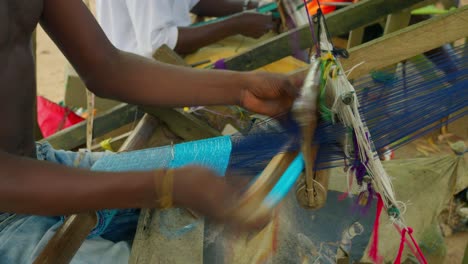 Ghanaian-man-making-Kente-handwoven-cloth-with-looms-rustic-equipment