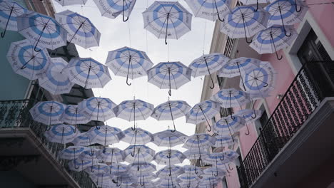 Slow-motion-tilting-shot-of-symmetrical-umbrellas-hanging-in-the-streets-of-San-Juan