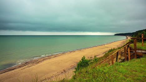 Timelapse-of-a-beach-with-dark-clouds-over-the-coast,-waves-crashing-on-the-shore-on-a-rainy-afternoon