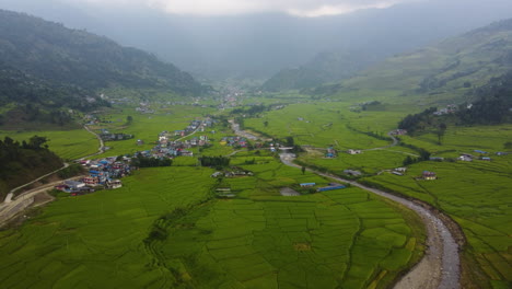 Antena-Que-Establece-Una-Mierda-De-Región-Rural-En-Pokhara-Con-Un-Pequeño-Pueblo-Y-Campos-Agrícolas-Tropicales-Entre-Montañas-Durante-El-Día-Brumoso