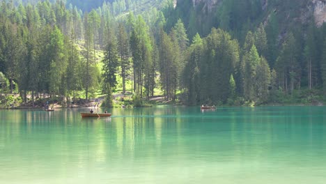 People-rowing-and-hiking-on-a-sunny-day-in-wooded-Lago-di-Braies,-Italy