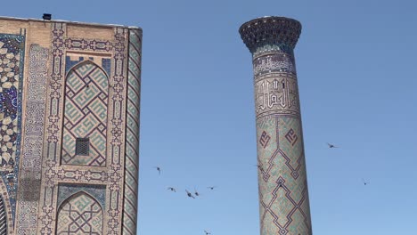 Birds-circle-Ulugh-Bek-Madrassah's-minaret-in-Registan-Square,-Samarkand,-Uzbekistan