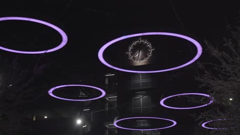 Large-Analog-Clock-on-Brick-Building-behind-Glow-Purple-Rings