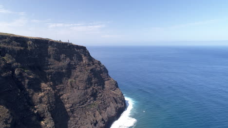 Madeira,-Ponto-da-Pargo-Lighthouse-aerial-coastal-shot-tracking-by-the-cliffs