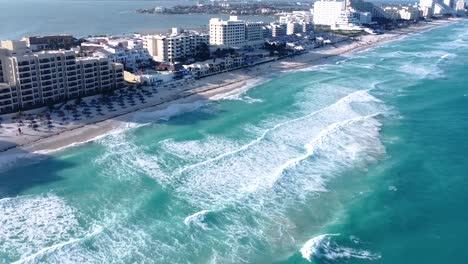 Wide-revealing-aerial-shot-of-Cancun-beach-in-the-hotel-zone-in-the-summer-and-sunny-day,-drone-footage-with-waves-crashing-and-turquoise-blue-water