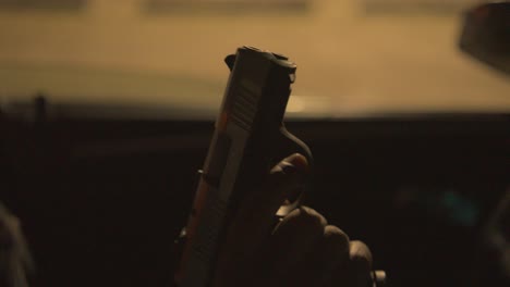 close-up-of-a-black-man-in-the-drivers-seat-of-a-car-ejecting-a-bullet-from-his-handgun