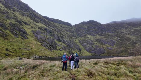 Hillwalkers-Mountainside-group-of-hillwalkers-at-Coumdala-Lake-in-The-Comeragh-Mountains-Waterford-Ireland-on-a-cold-winter-day