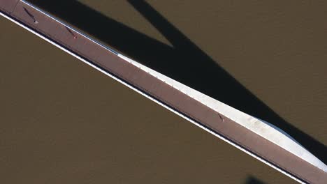 Aerial-shot-of-a-sleek-bridge,-Puente-de-la-Mujer,-casting-long-shadows-on-the-water,-a-minimalist-urban-scene
