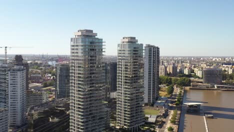 Modern-high-rise-buildings-tower-over-the-riverfront-in-Buenos-Aires,-against-a-sprawling-city-backdrop