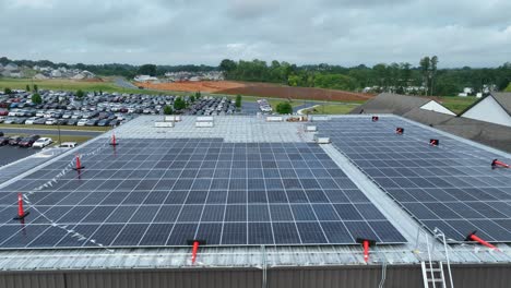 Solar-panels-on-a-warehouse-roof-with-a-parking-lot-and-construction-in-the-background