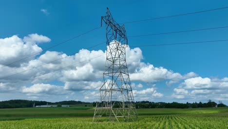 Electricity-pylon-towering-over-a-green-cornfield-with-a-blue-sky
