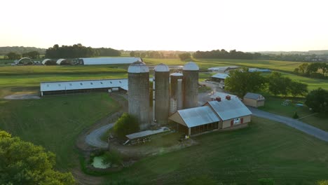 Sunset-over-a-farm-with-silos-and-long-barns-in-a-rural-landscape