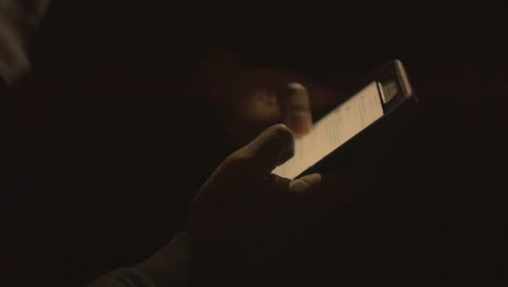 close-up-of-a-black-mans-hands-scrolling-his-phone-in-the-dark