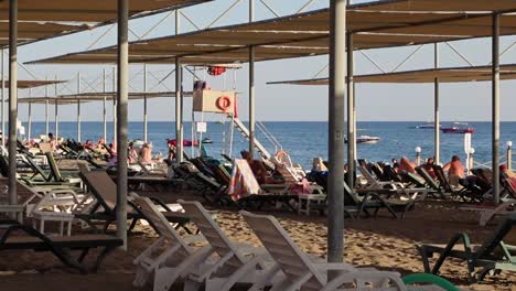 Static-shot-of-beach-with-sunbeds-and-sea-in-the-background-with-people