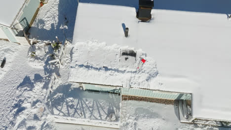 Aerial-view-around-partly-cleaned-solar-panels-on-a-snowy-house-roof,-winter-day