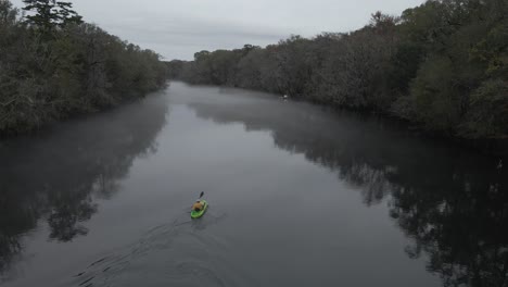 A-follow-shot-from-a-guy-on-a-kayak-paddling-to-mystic-and-dramatic-looking-fog-covering-the-dark-water-on-Edisto-river-in-USA