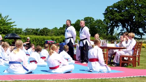 Zwei-Taekwondo-Lehrer-Sprechen-Während-Einer-Neuen-Gürtelzeremonie-Mit-Jungen-Taekwondo-Schülern