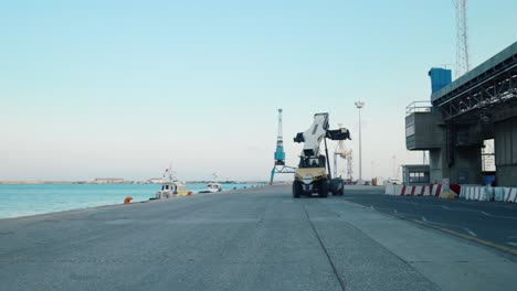 A-yellow,-unloaded-harbor-loader-drives-along-the-coast-in-Limassol-Marina